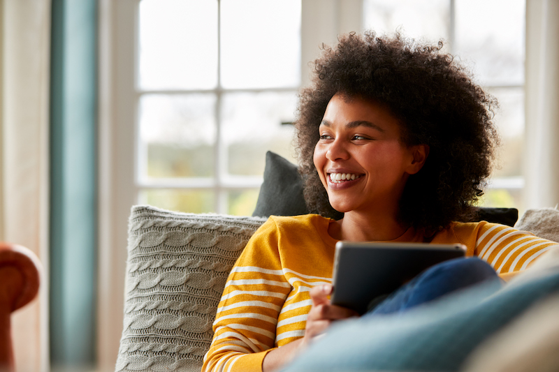 woman-relaxing-on-sofa-at-home-using-digital-table-2022-04-28-03-31-43-utc